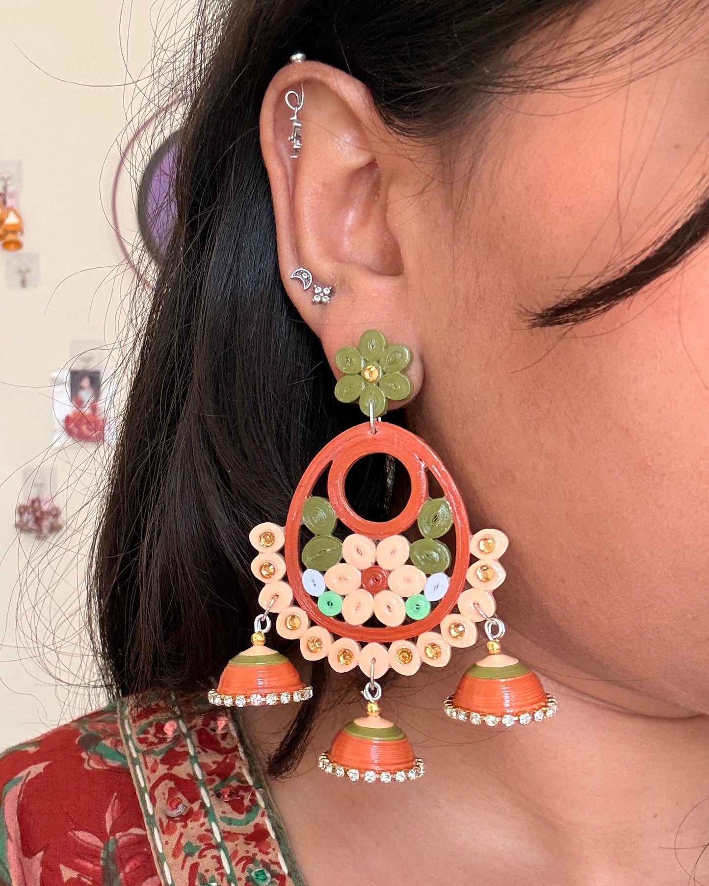 Close-up of a person wearing large, ornate earrings with a blurred background